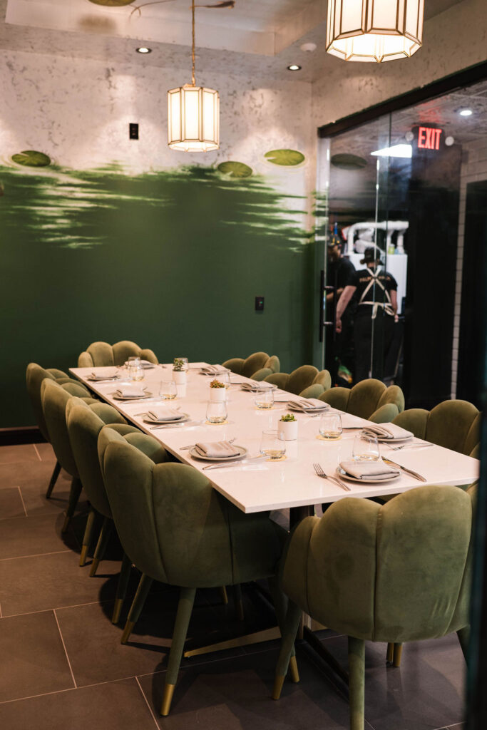 A private dining room at Palm Palm with green chairs, a long white table, and green painted walls.