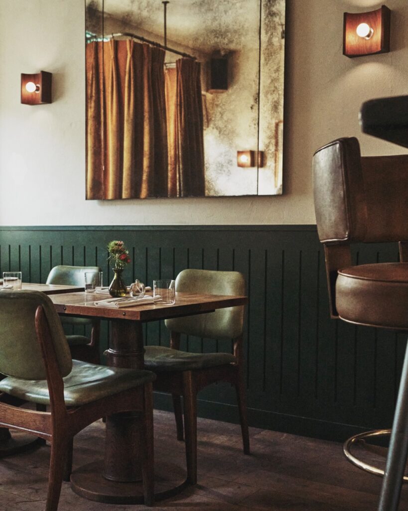 The inside of Strakers in. London with a small wooden table against a half green wall.