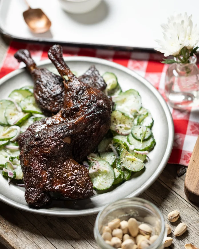 An aerial shot of Smoked Duck Leg Quarters playing on a bed of Cucumber Salad.