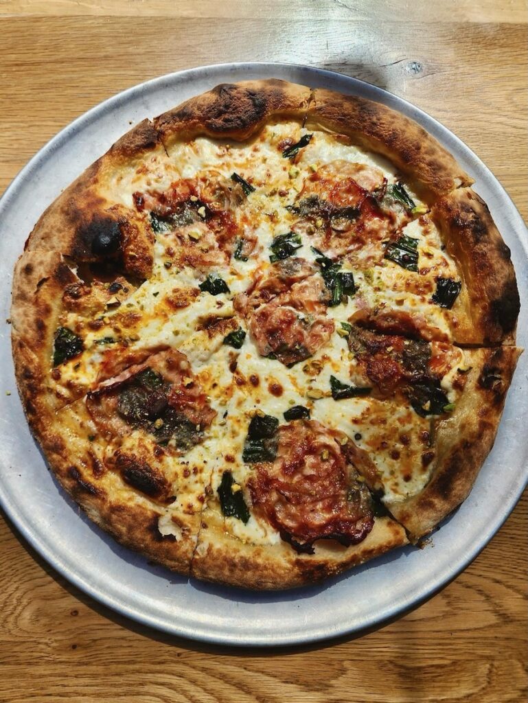 A pizza from Alta Via on a brown table.