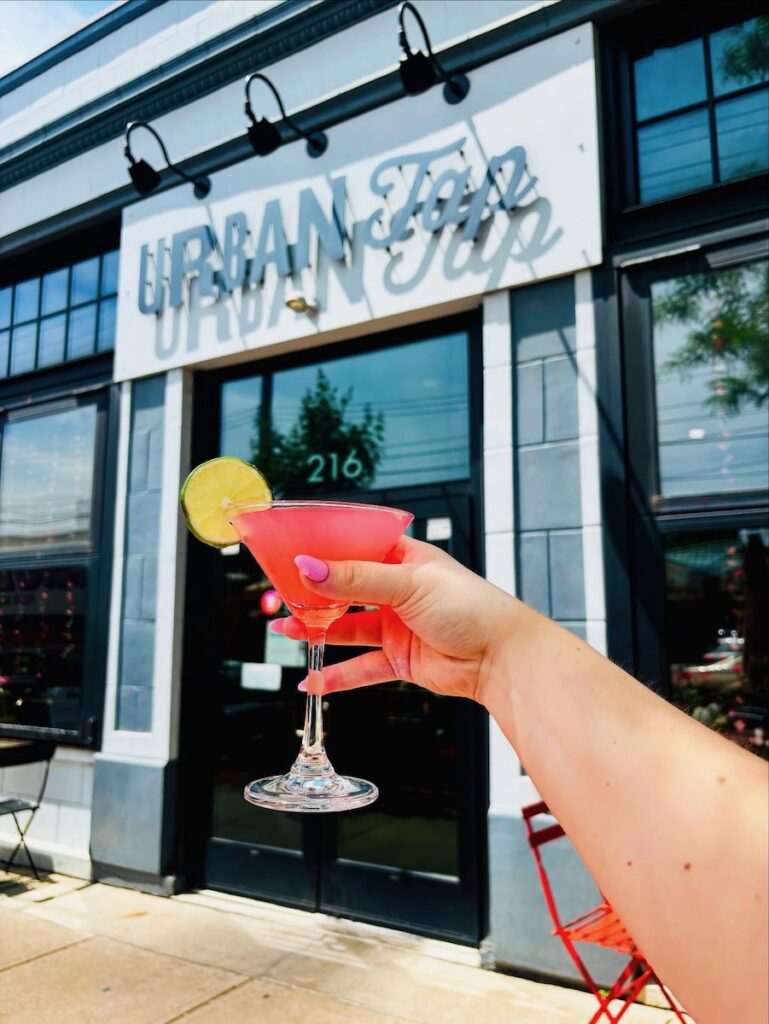 A hand holds a martini outside of Urban Tap