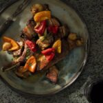 An aerial shot of a gray/blue/green plate holding a Pork Chop with Bacon and Pickled Peppers