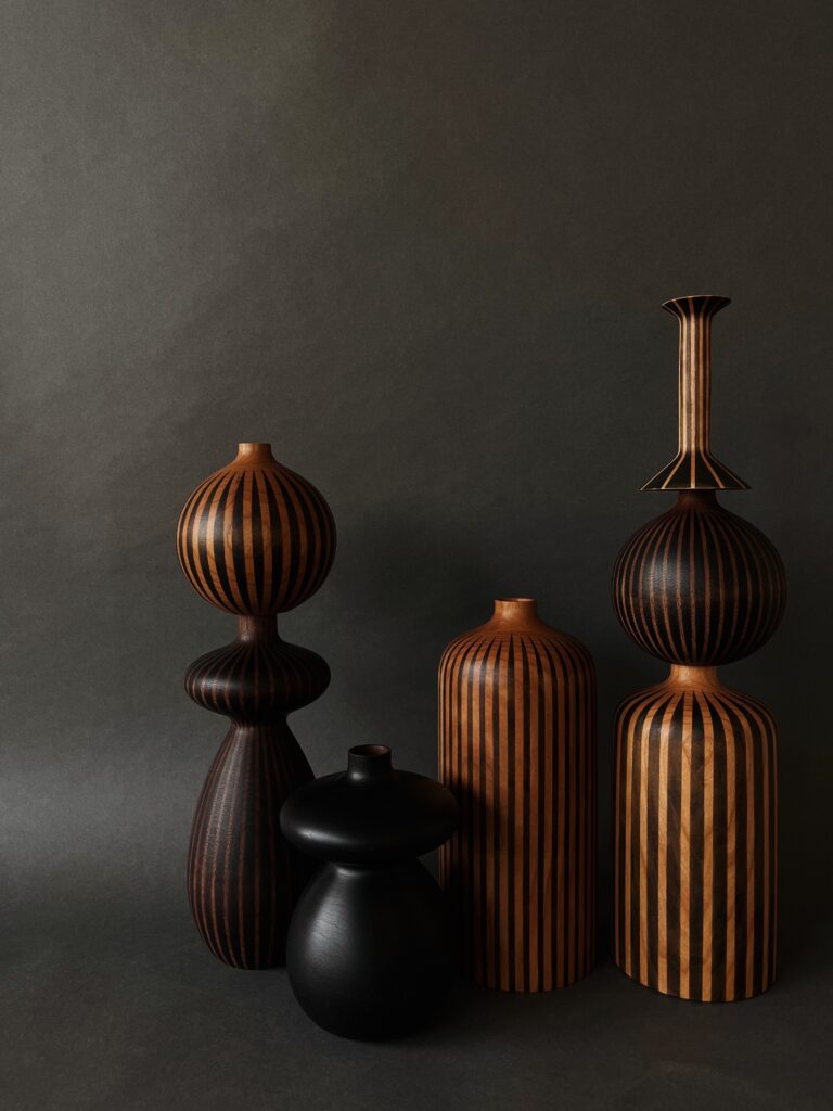 A collection of vases and candleholders made of ebonized cherry and walnut.