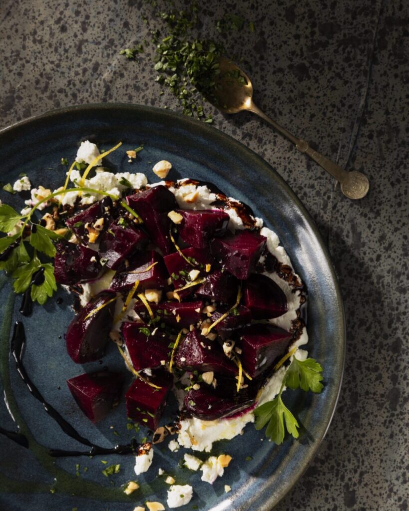 An aerial shot of a dark blue plate holding a serving of roasted beets