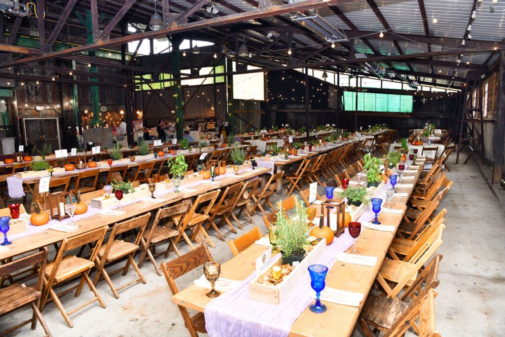 Wood tables in an event space lined with wood chairs and place settings. 