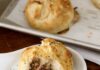 Beef and Onion Knishes Partially eaten Beef and Caramelized Onion Knishes served on a ceramic plate with a knife on the side.