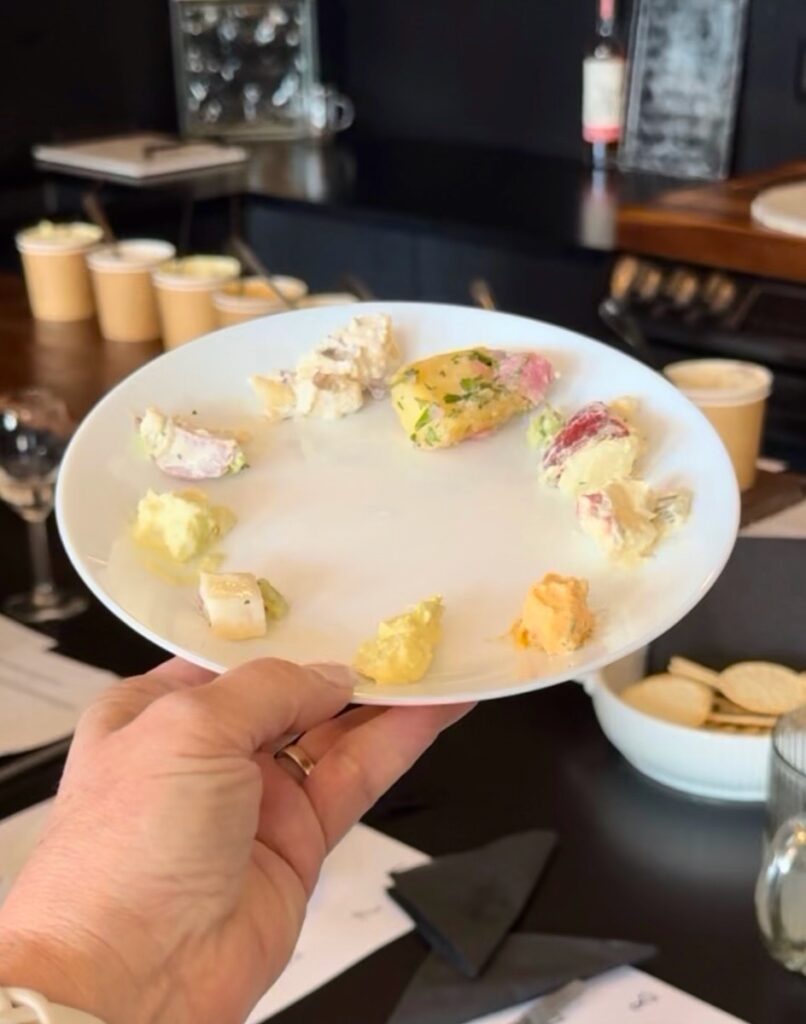 A person holds a plate of potato salad samples.