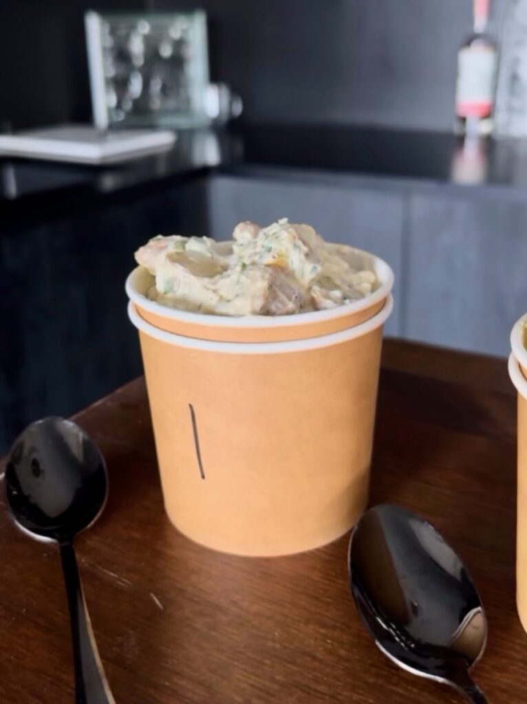 A small brown cup holds potato salad inside.
