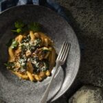 An aerial shot of a gray stone bowl filled with GNOCCHI WITH BRAISED OXTAIL AND COLLARD GREENS.