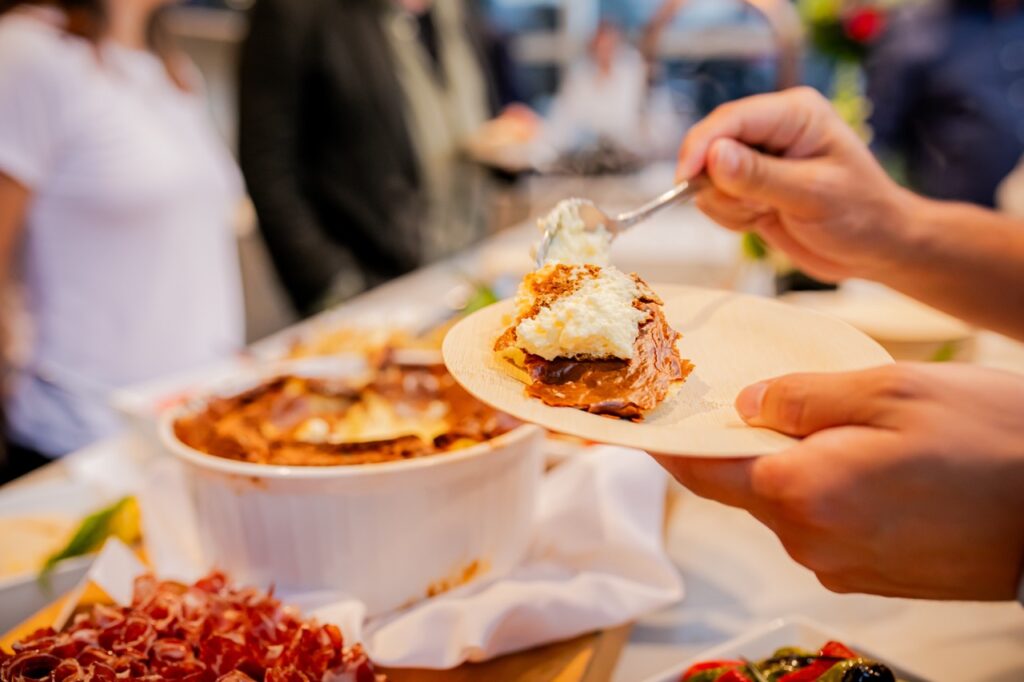 A person scoops pasta onto their plate.