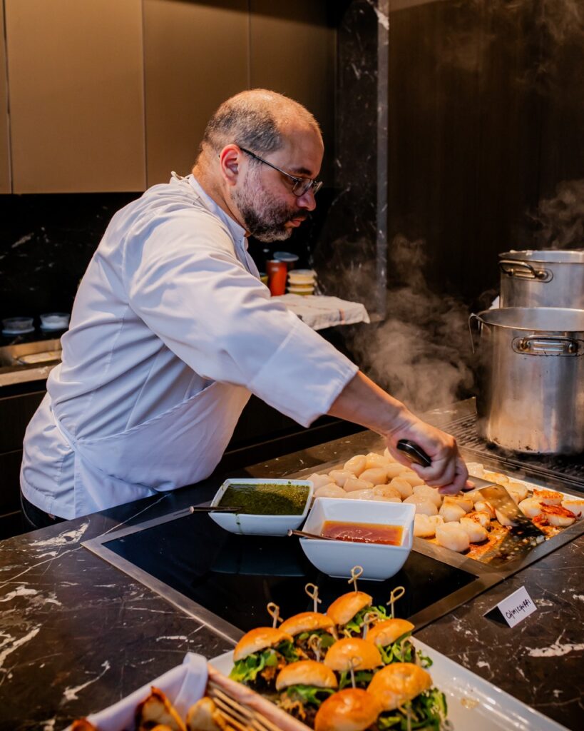 A chef cooks scallops on a grill.