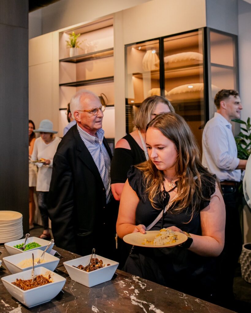 A woman grabs food from the table.