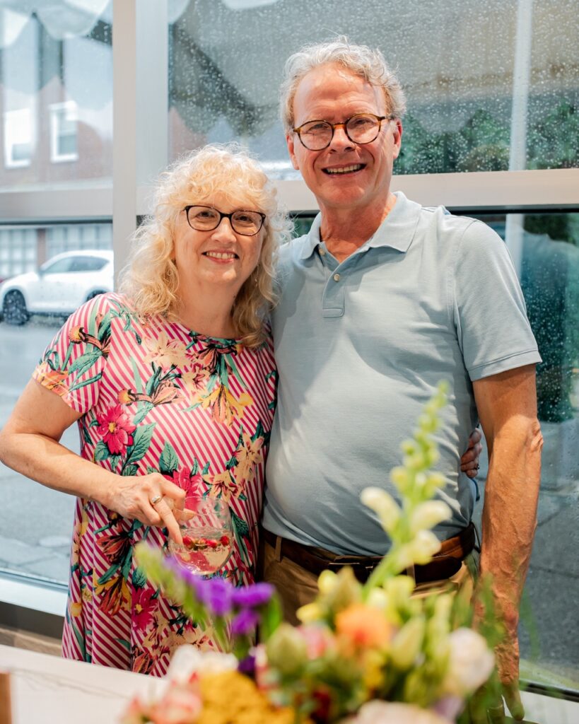 A man and woman in glasses stand together.