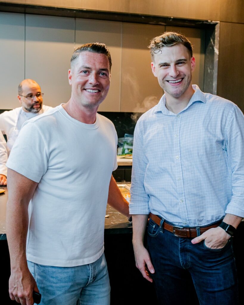 Two men stand together in the kitchen.