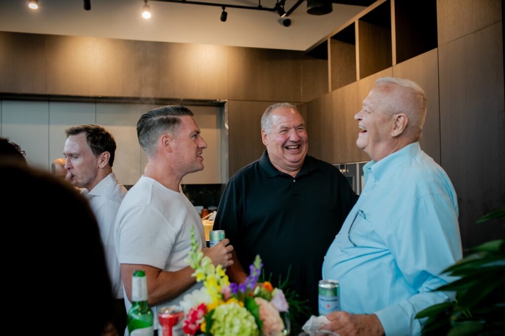 Three men laugh together.