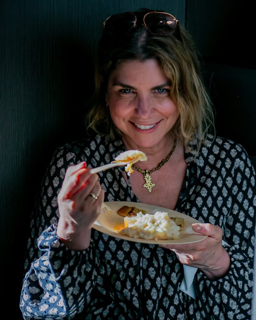 A woman with sunglasses eats from a plate.