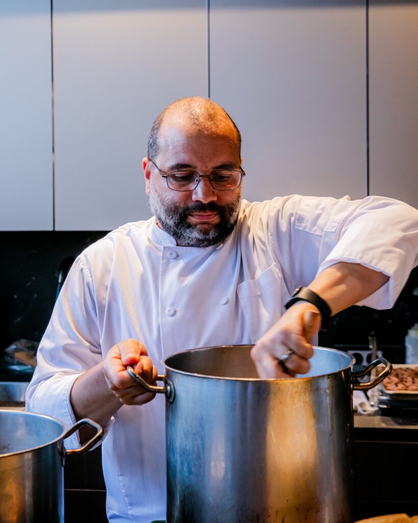 A chef stirs a big metal pot.
