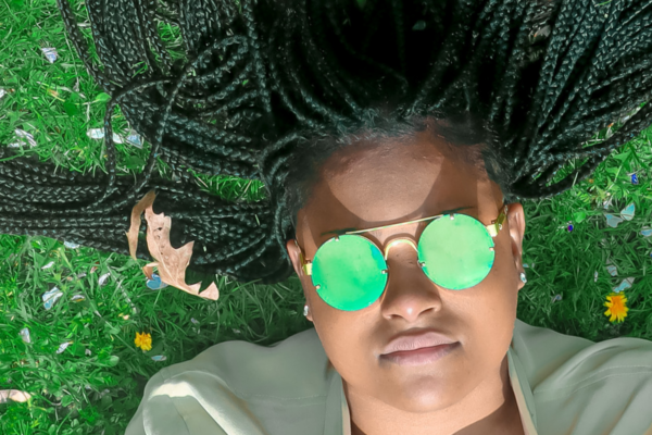 Rickia Davenport - The Choice, laying in the grass with green sunglasses