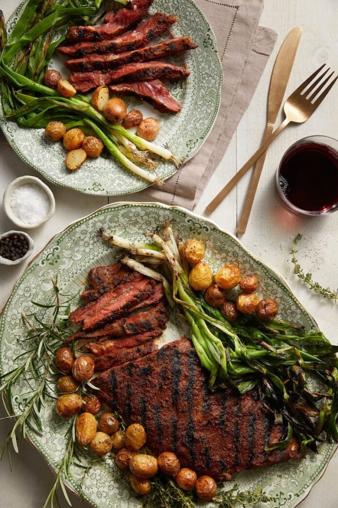 Fall Spice-Rubbed Skirt Steak served on two dishes with vegetables, salt, and pepper