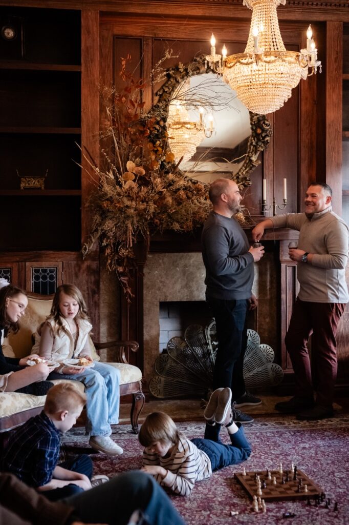 Kids play in the corner of the living area with two men talking at the fireplace.