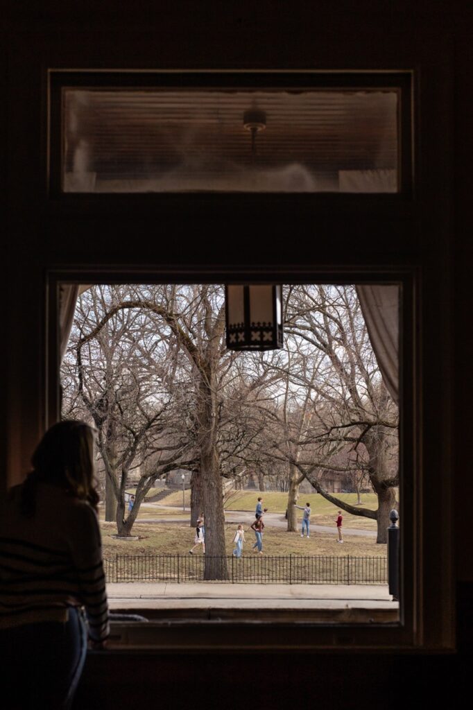 A window shows out into the fall backyard where children are.