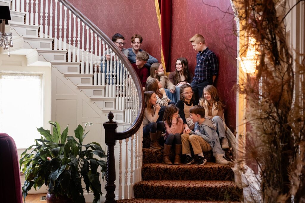 A group of children sit on the stairs of a home.