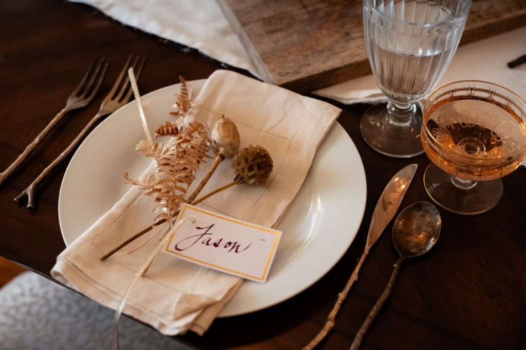 A plate setting with dried flowers and a khaki napkin.