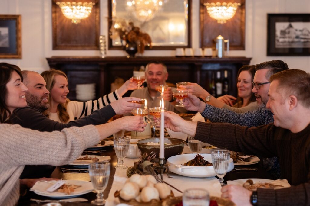 People at a friendsgiving table cheers drinks.
