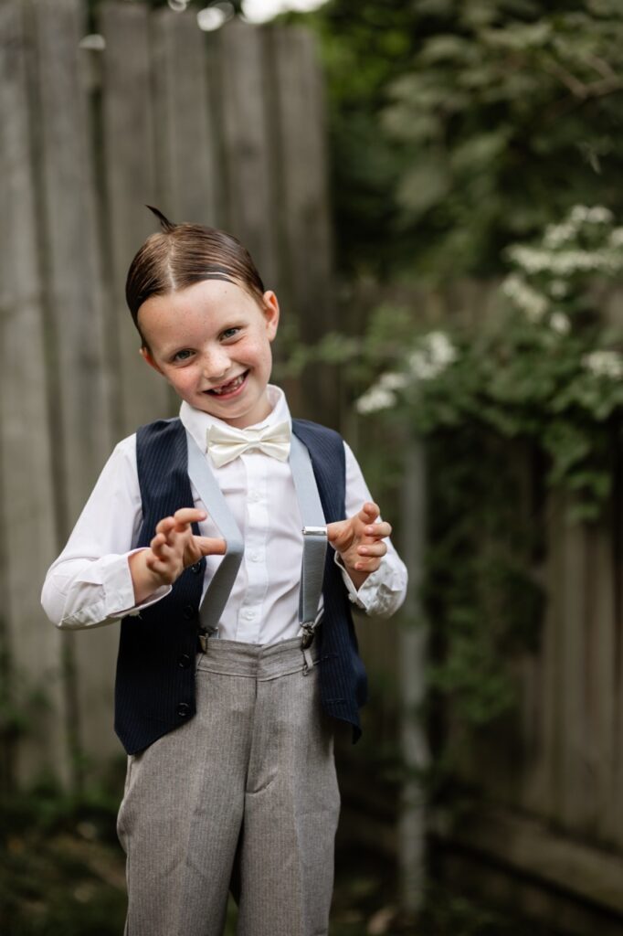 A little kid wears a costume with suspenders and a vest.