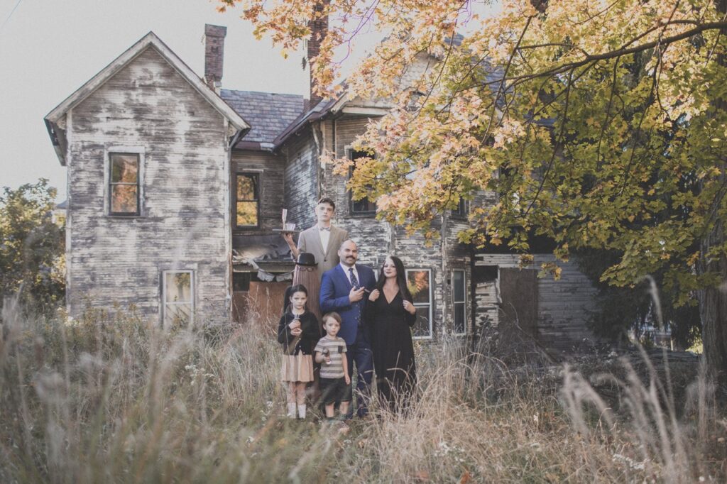 A family dressed as the Addams family in front of a creepy house.