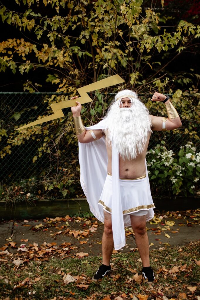 A man stands outside in a Zeus costume.