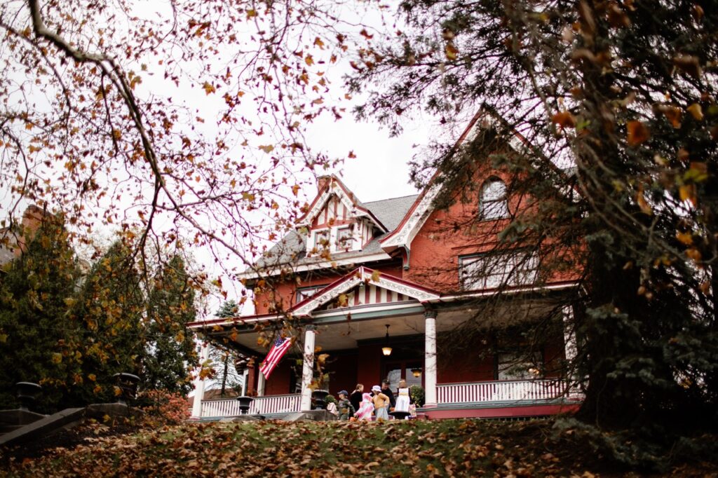 Kids stand on the porch of a large house.