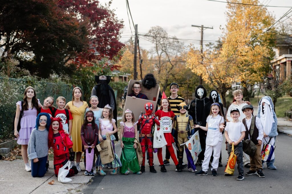 A large group of children in Halloween costumes outside.