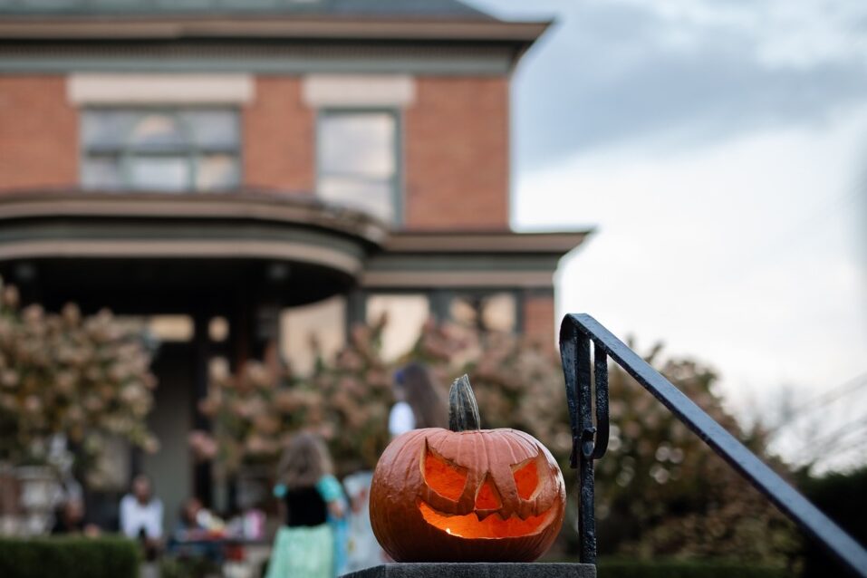 A carved pumpkin sits on a banister outside the home.