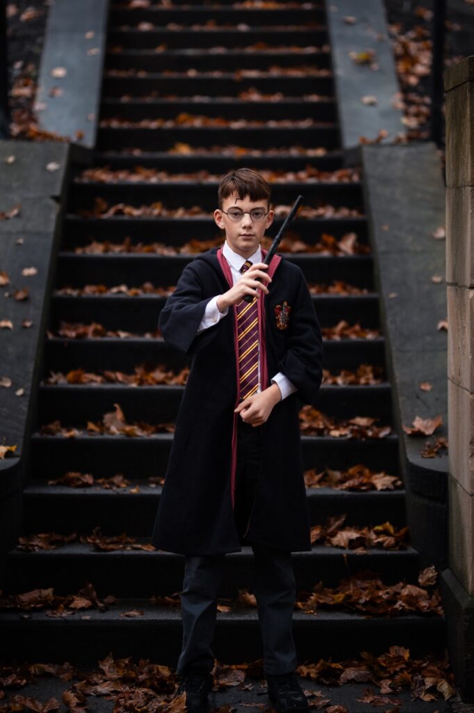 A boy dressed as Harry Potter with a wand.