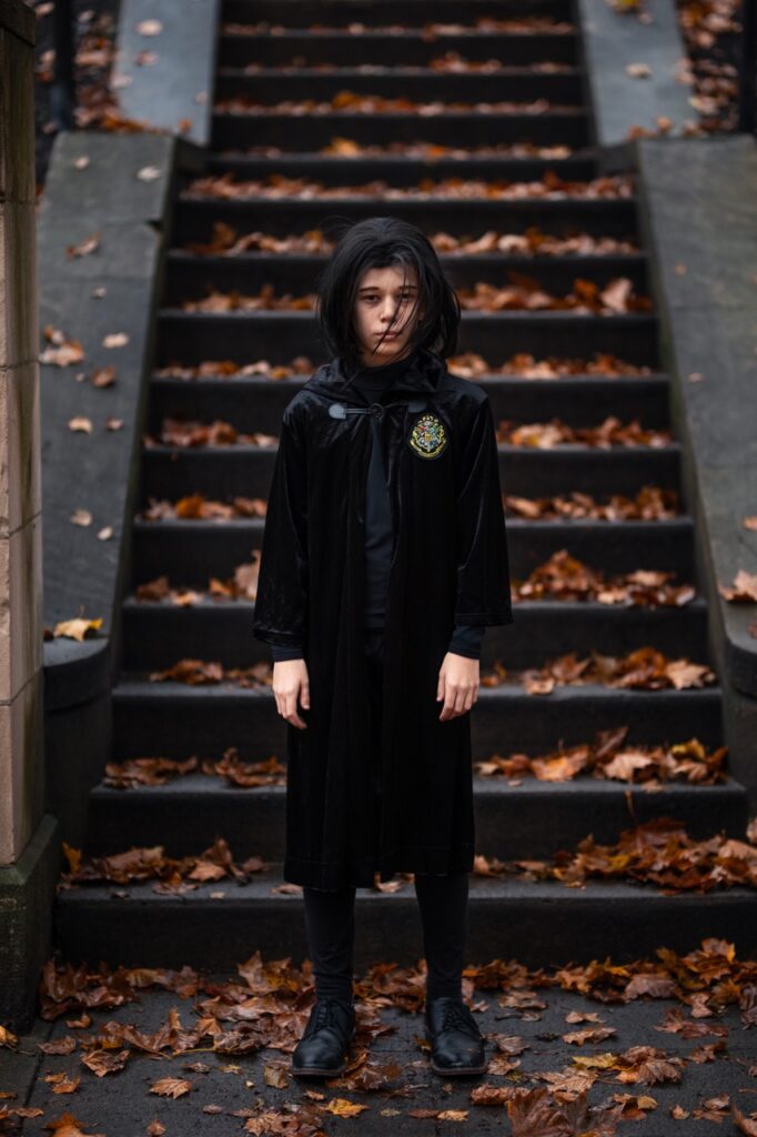 A boy in a robe in front of a set of stairs.