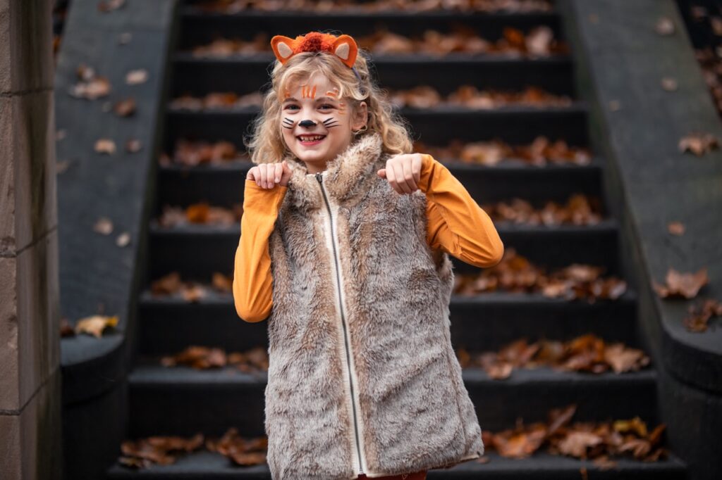 A girl poses as a tiger in front of stairs.