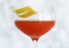Jack Rose Cocktail A stemmed glass filled with a pinkish-red Jack Rose cocktail, garnished with a spiral of lemon peel.