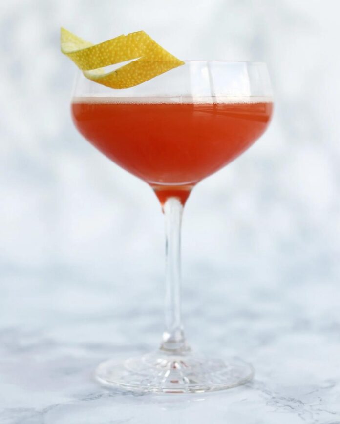 Jack Rose A stemmed glass filled with a pinkish-red Jack Rose cocktail, garnished with a spiral of lemon peel.