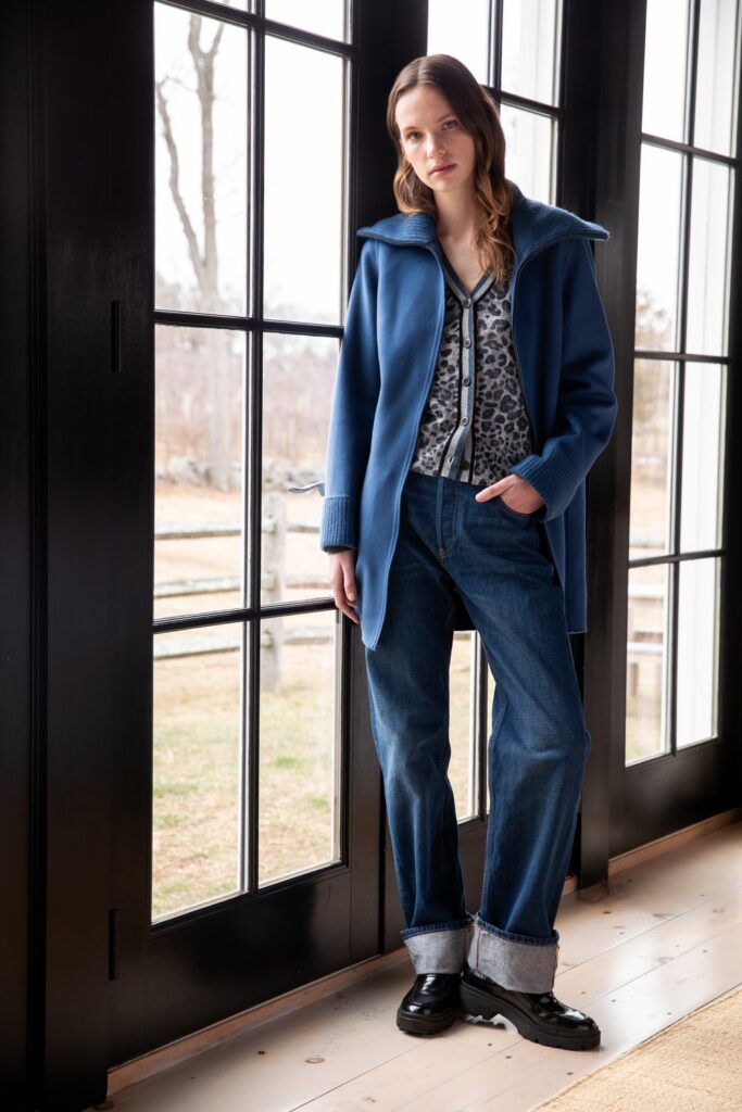a white female model stands in front of a windo wearing a Knit trim zip mock coat in blue and matching pants