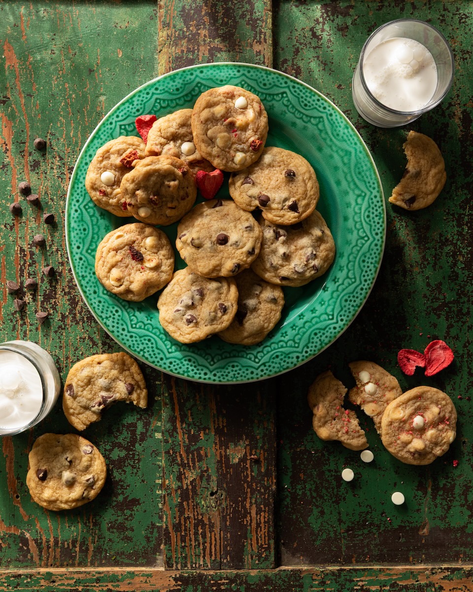 A green plate full of Martha Stewart cookies in chocolate chip and white chocolate strawberry varieties.