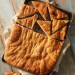 A sheet pan holds a Focaccia load inspired by Martha Stewart that's slices in half and then has half of one half slices into triangles.