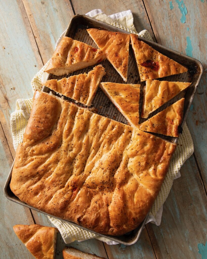 A sheet pan holds a Focaccia load inspired by Martha Stewart that's slices in half and then has half of one half slices into triangles.