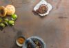 Mexican Mole Sauce: Two Ways A flat lay photo showing ingredients for Mexican mole sauce, including various chiles, nuts, spices, and a stone mortar and pestle on a rustic metal surface.