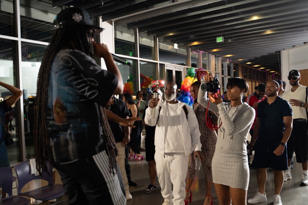 A group of people take photos of a performer with long braids on stage.