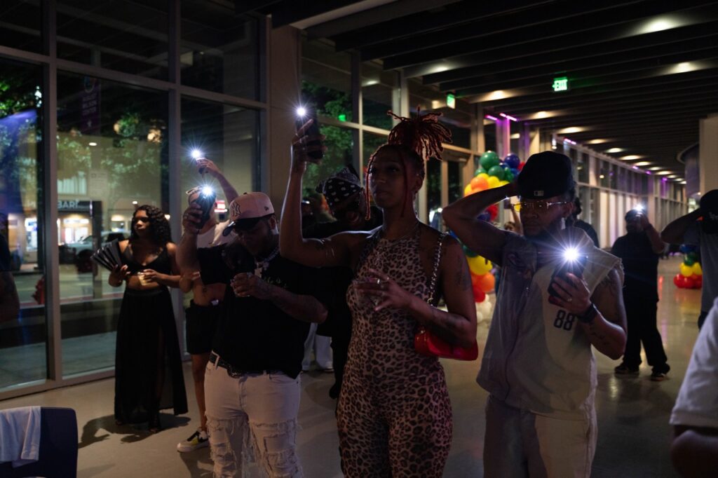A group of people hold their phone flashlights in the air.