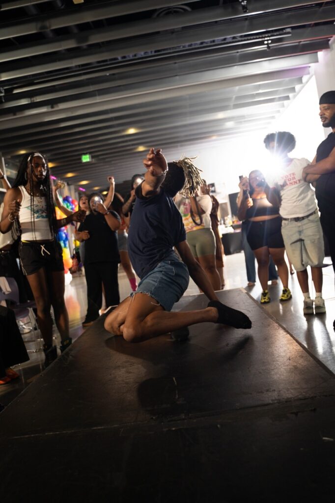 A person in jean shorts and a t shirt drops down while dancing on stage.
