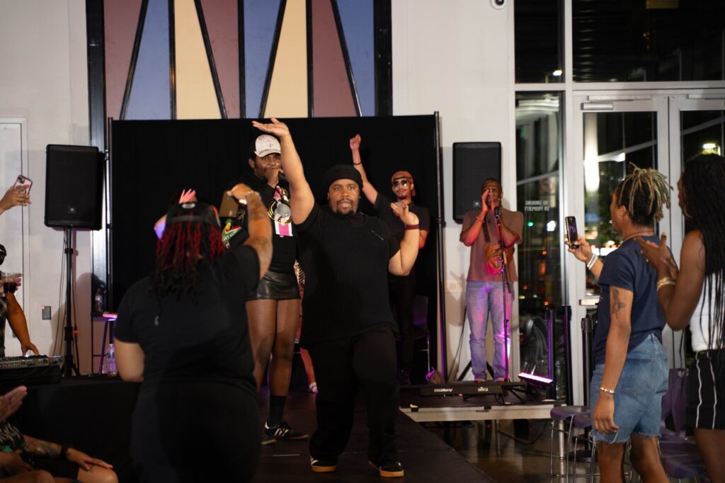 A group of people on stage hold one hand up in the air.