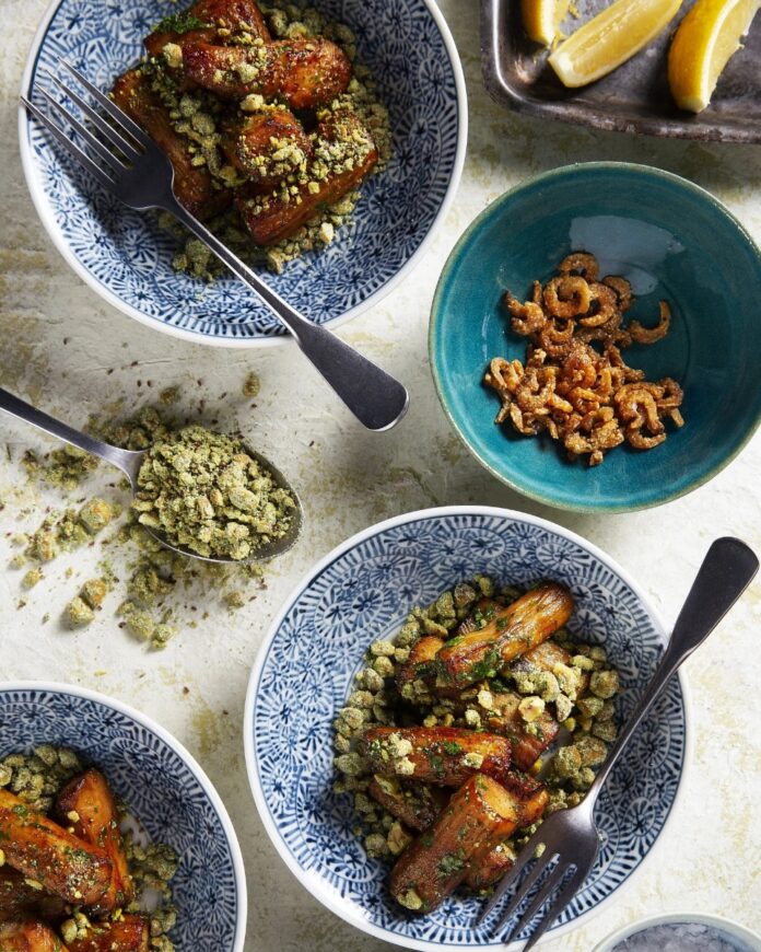 Roasted Eggplant with Anchovy and Almond Crumble Blue-and-white patterned bowls filled with roasted eggplant, topped with a green crumble, with a separate bowl of dried anchovies.