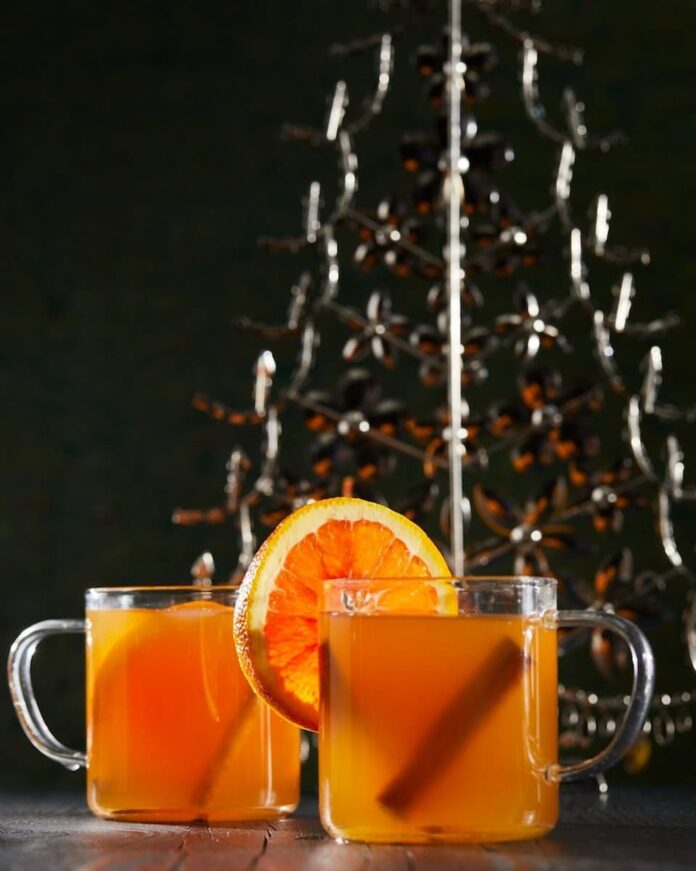 A vibrant and eye-catching spiked cider featuring a delightful mix of fall flowers and foliage. The arrangement showcases the warm hues of orange, red, and yellow, perfectly capturing the essence of the season.